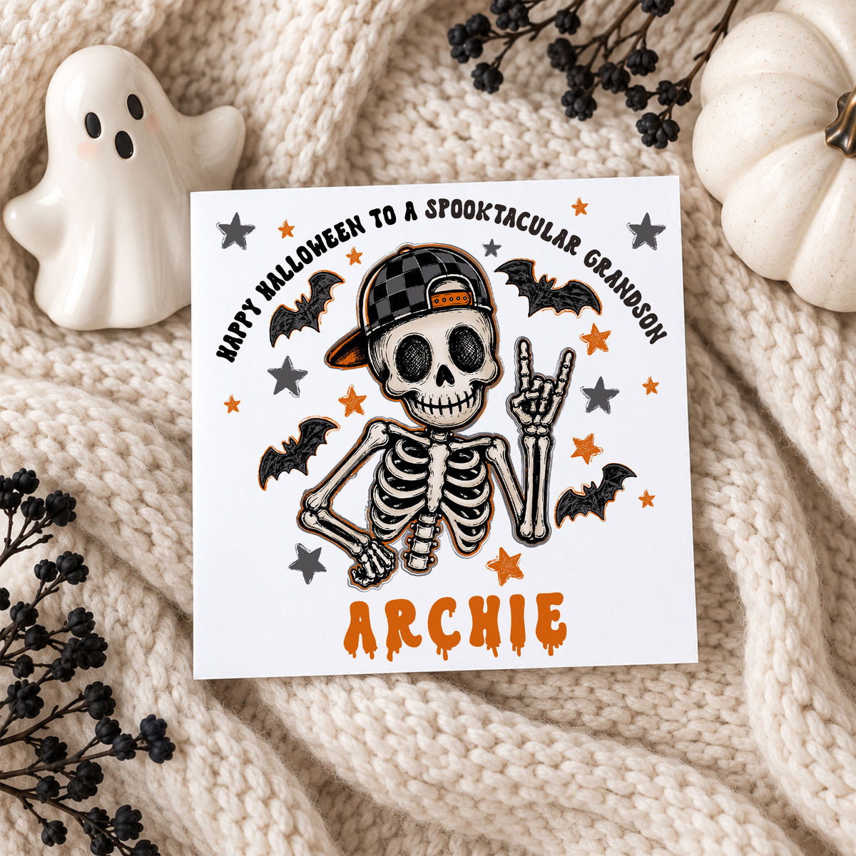 Personalised skeleton Halloween card for boys featuring a hand-drawn skeleton wearing a black checked baseball cap, surrounded by black bats and orange and grey stars. Personalised with a name and relation, suitable for Son, Grandson, Nephew, Godson, Brother or a special little boy.