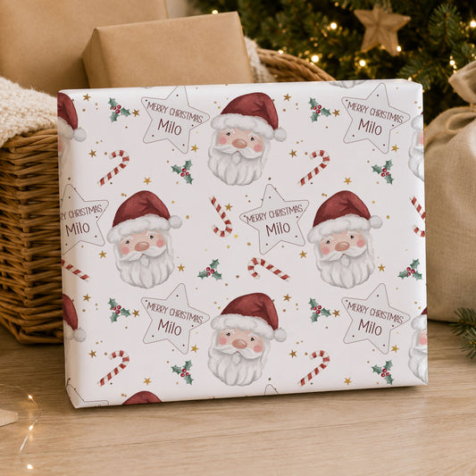 Personalised Santa Christmas wrapping paper featuring Santa faces, candy canes, holly and stars with the child’s name.