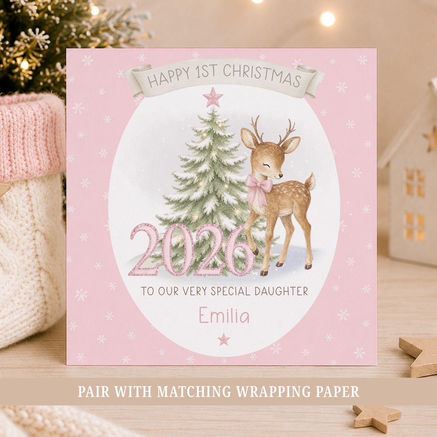 Personalised baby girl First Christmas card featuring a reindeer with pink bow, snowy Christmas tree, pink 2026 numbers, stars and snowflakes.