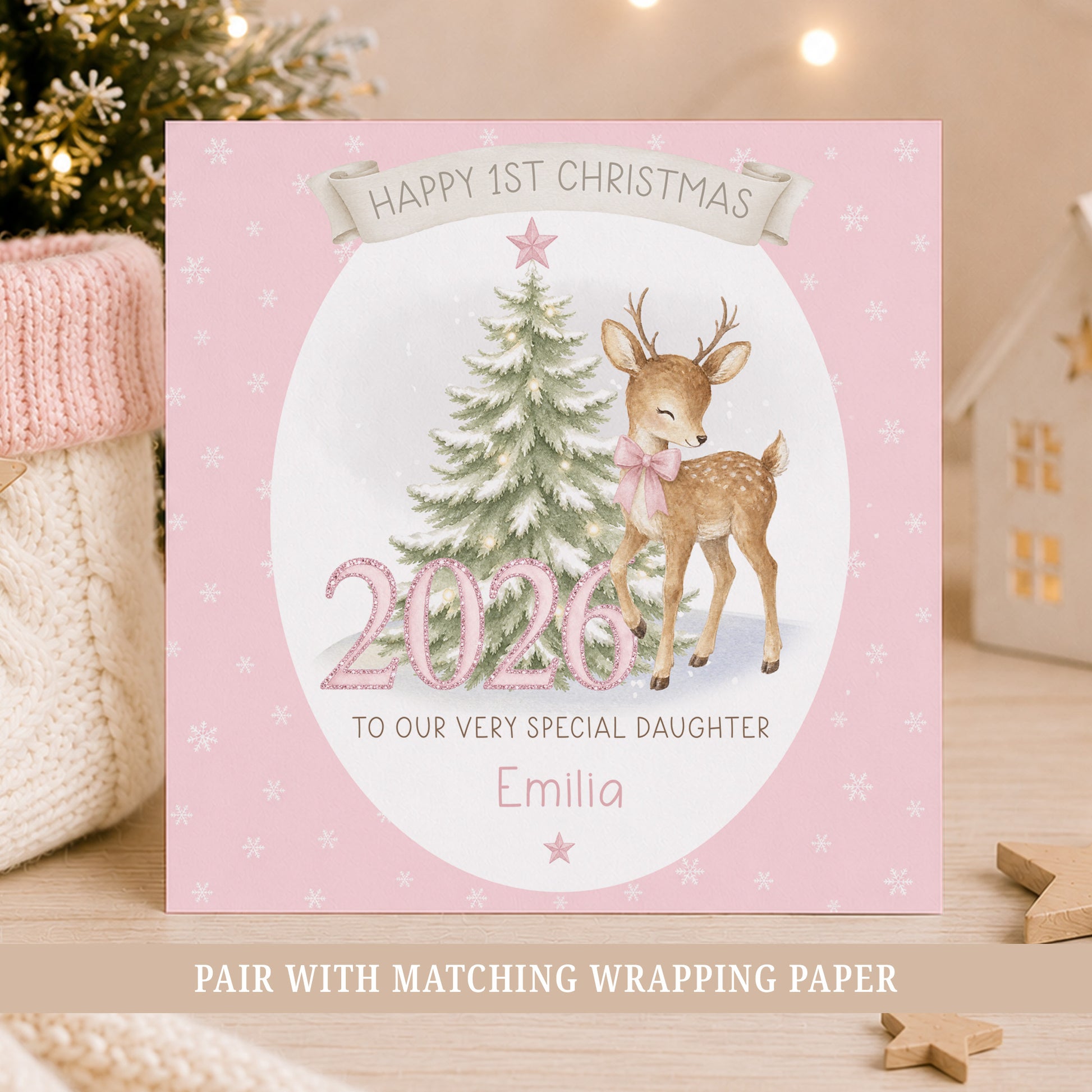 Personalised baby girl First Christmas card featuring a reindeer with pink bow, snowy Christmas tree, pink 2026 numbers, stars and snowflakes.