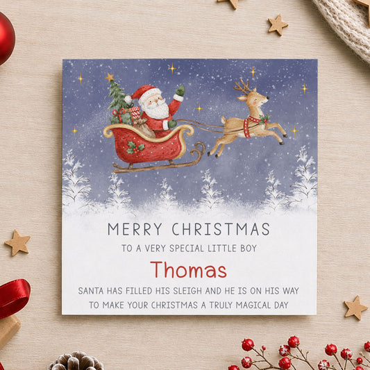 Personalised children’s Christmas card featuring Santa in a red sleigh with his reindeer flying over a snowy winter scene, personalised with any relation and child’s name.