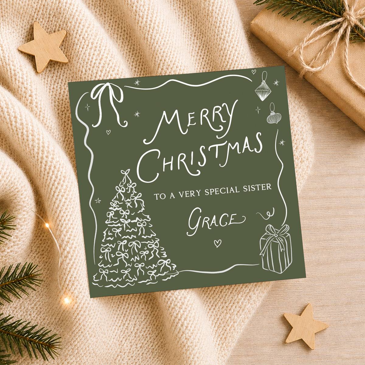 Personalised green Christmas card featuring white hand-drawn Christmas tree, bows, hanging baubles and wrapped present illustrations. Finished with Merry Christmas lettering and personalised with the recipient's name and relation. Examples shown for Daughter Amelia, Sister Grace and Niece Natasha.