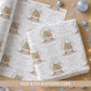 Personalised blue first Christmas wrapping paper featuring a teddy bear in a Christmas snow globe with blue hearts, gold snowflakes and the child’s name, relation and year.