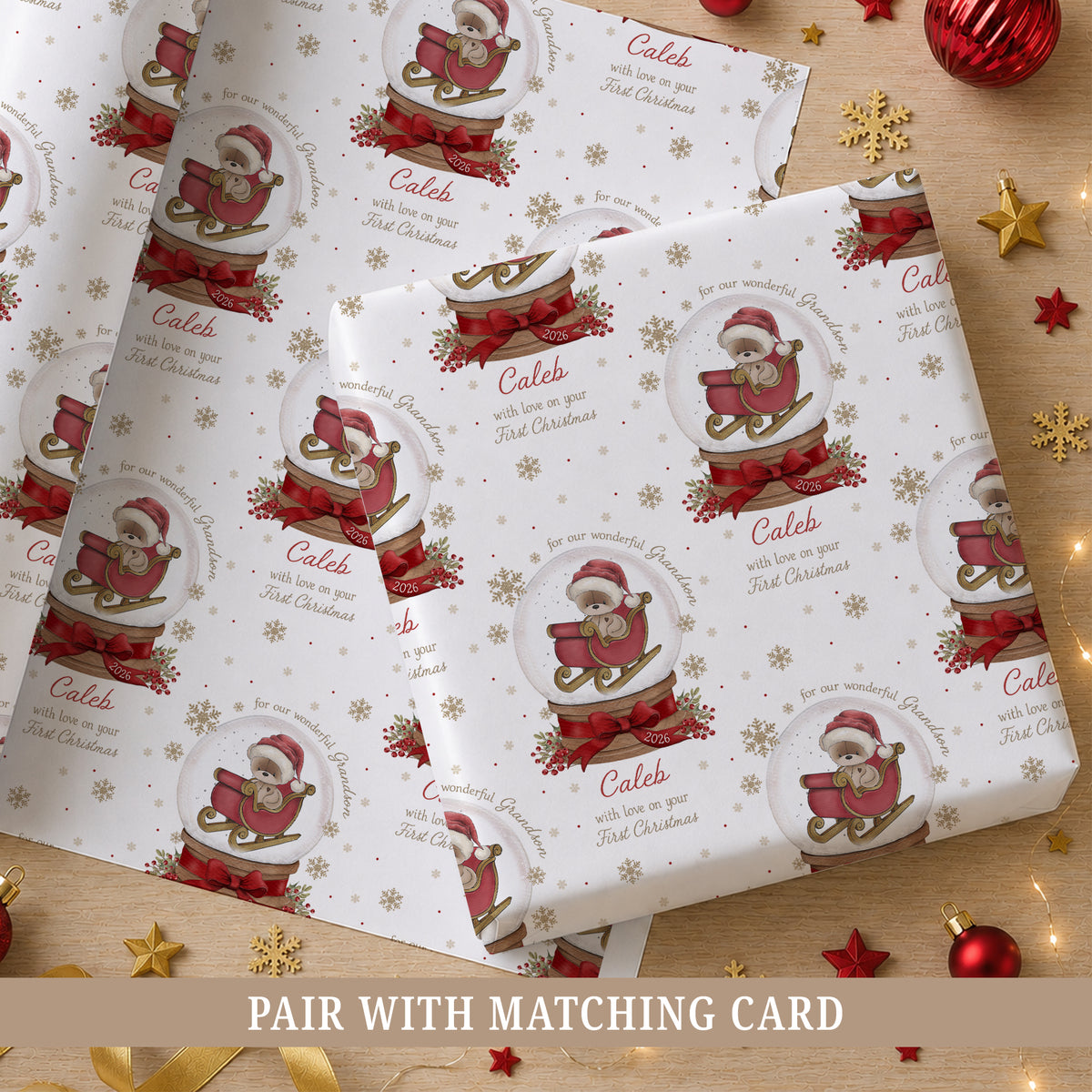 Personalised Grandson First Christmas wrapping paper featuring a teddy bear in a red sleigh inside a Christmas snow globe, with red bows, berries and gold snowflakes. Personalised with a name, relation and year and suitable for Grandson, Son, Nephew or Godson.