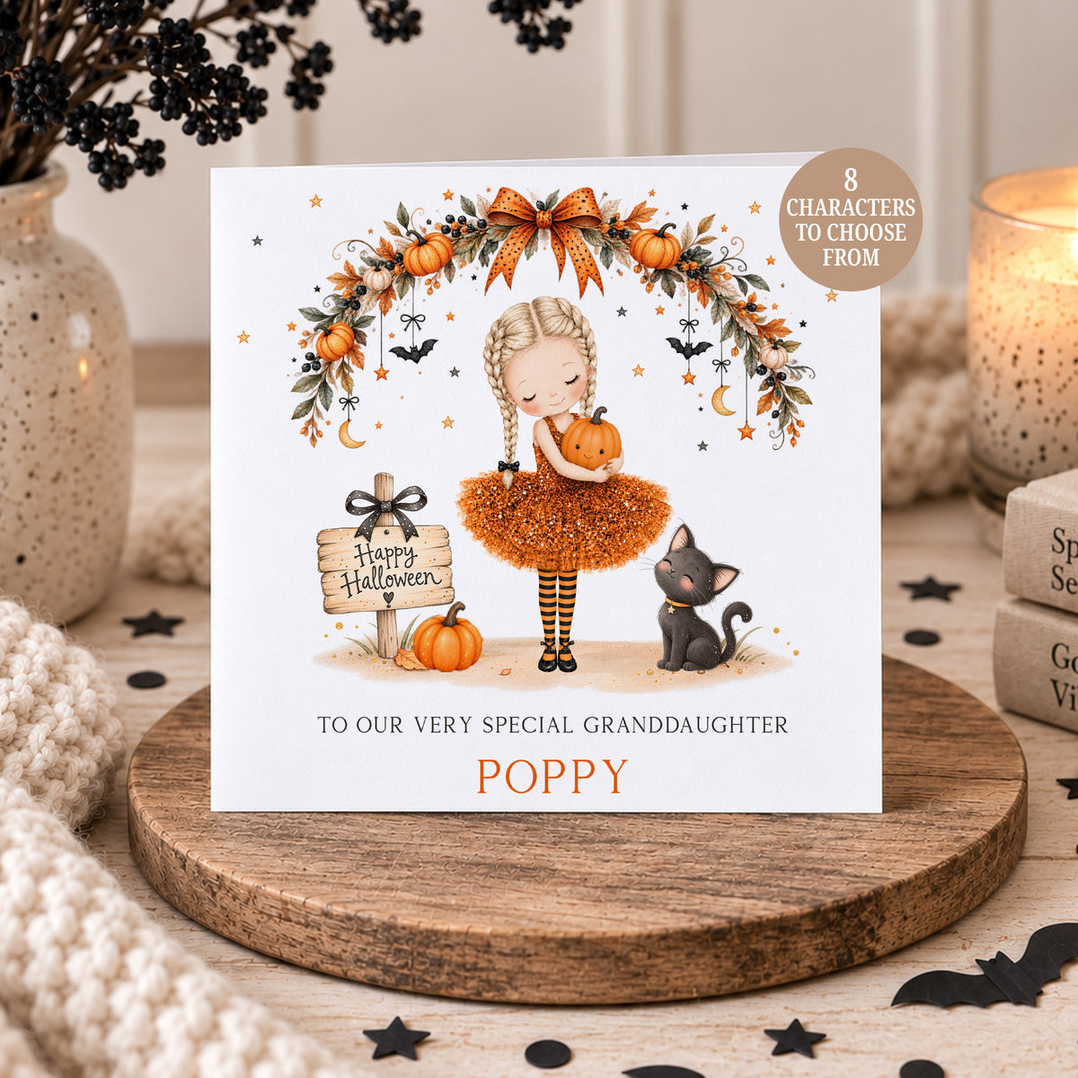 Personalised Granddaughter Halloween card featuring a girl in an orange Halloween dress holding a pumpkin, with a black cat, pumpkins, bats and autumn garland. Personalised with any name and relation, with 8 different character options available including different hair colours and skin tones.