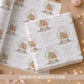 Personalised pink first Christmas wrapping paper featuring a teddy bear in a Christmas snow globe with pink hearts, snowflakes and the child’s name, relation and year.