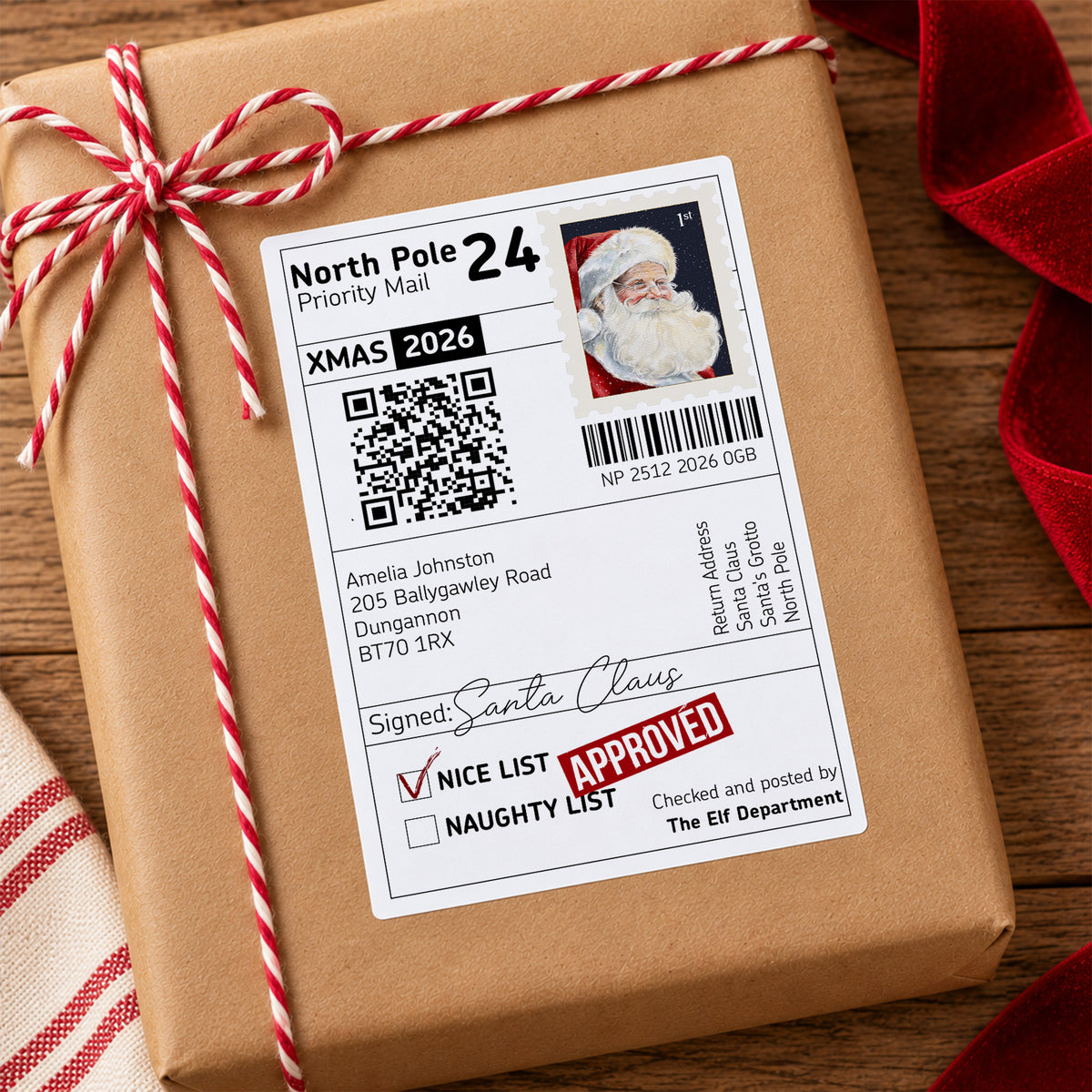 Personalised North Pole Santa delivery sticker measuring 4x6 inches, designed as a Christmas parcel label from Father Christmas. Features a Santa Claus postage stamp, North Pole Priority Mail wording, personalised child's name and address, Nice List Approved stamp, Santa's signature, barcode and interactive QR code to track Santa on Christmas Eve. Large glossy Christmas gift sticker shown on wrapped presents, ideal for creating a special delivery from Santa.