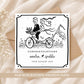 Personalised wedding card featuring a bride and groom riding a bicycle, customised with the couple's names and wedding date.