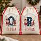 Personalised kids Christmas sack featuring a large navy initial decorated with snowflakes alongside Santa, a reindeer and penguin, with “Special Delivery For” above and the child's chosen name printed underneath. Natural poly linen Santa sack with a red drawstring, available in two sizes.
