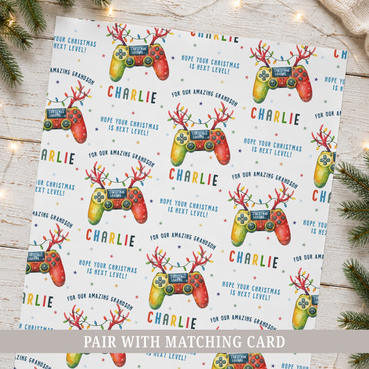 Personalised gamer Christmas wrapping paper featuring colourful festive game controllers, Christmas lights, stars and the recipient’s name.