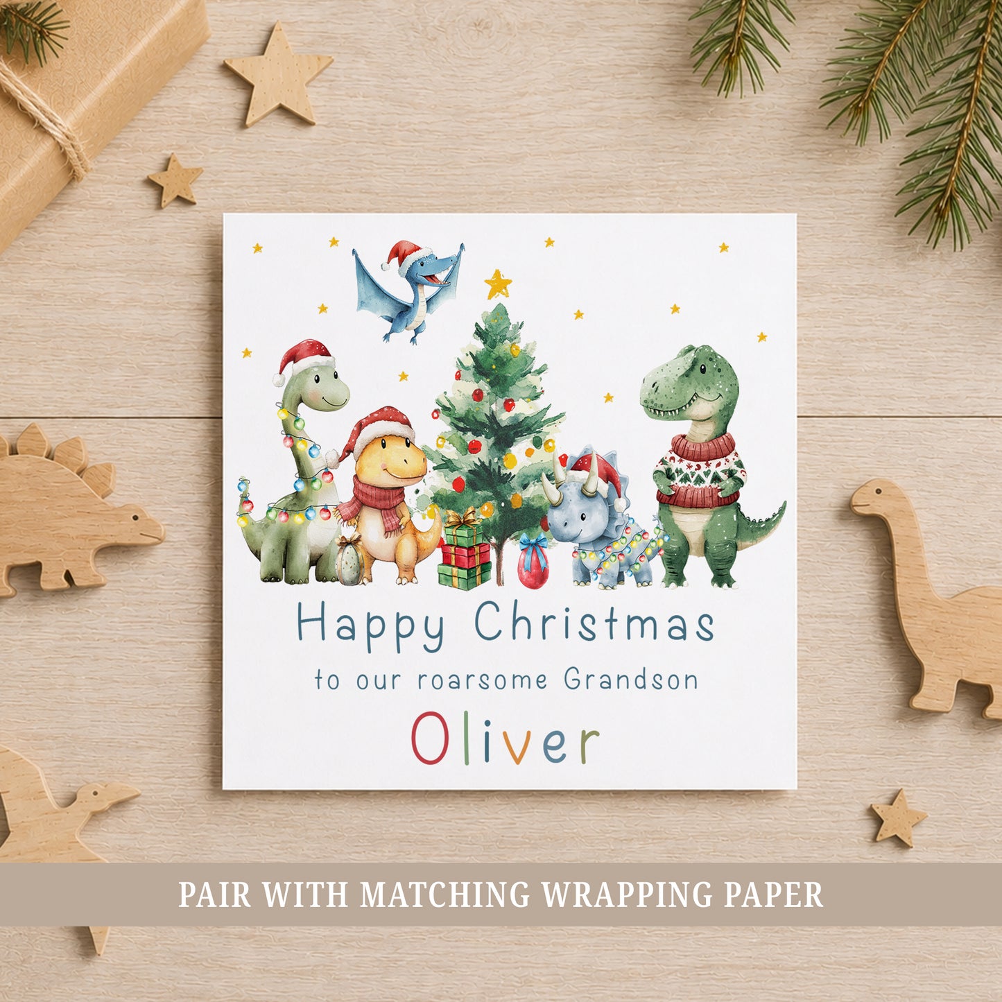 Personalised dinosaur Christmas card featuring festive dinosaurs in Santa hats around a Christmas tree, customised with name and relation.