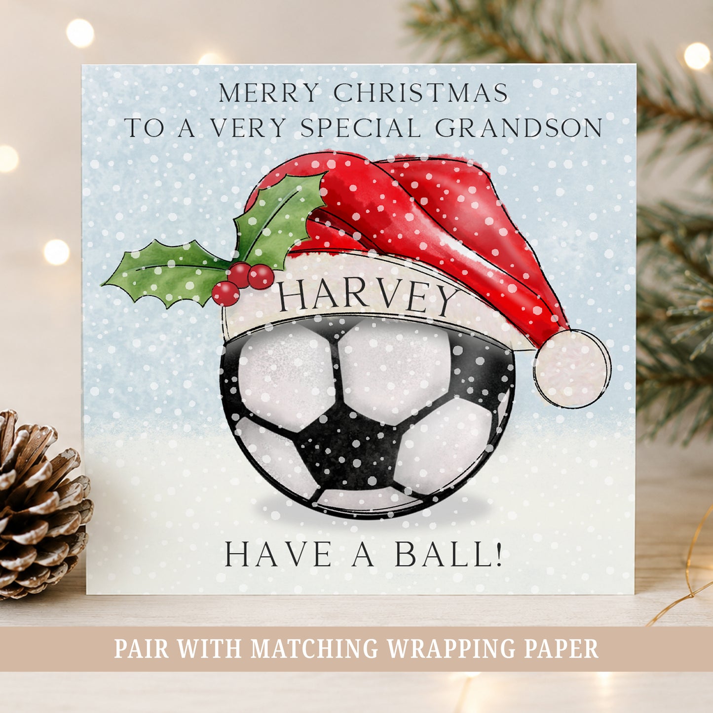 Personalised football Christmas card for boys featuring a football in a Santa hat, child’s name and Grandson wording on a snowy blue background