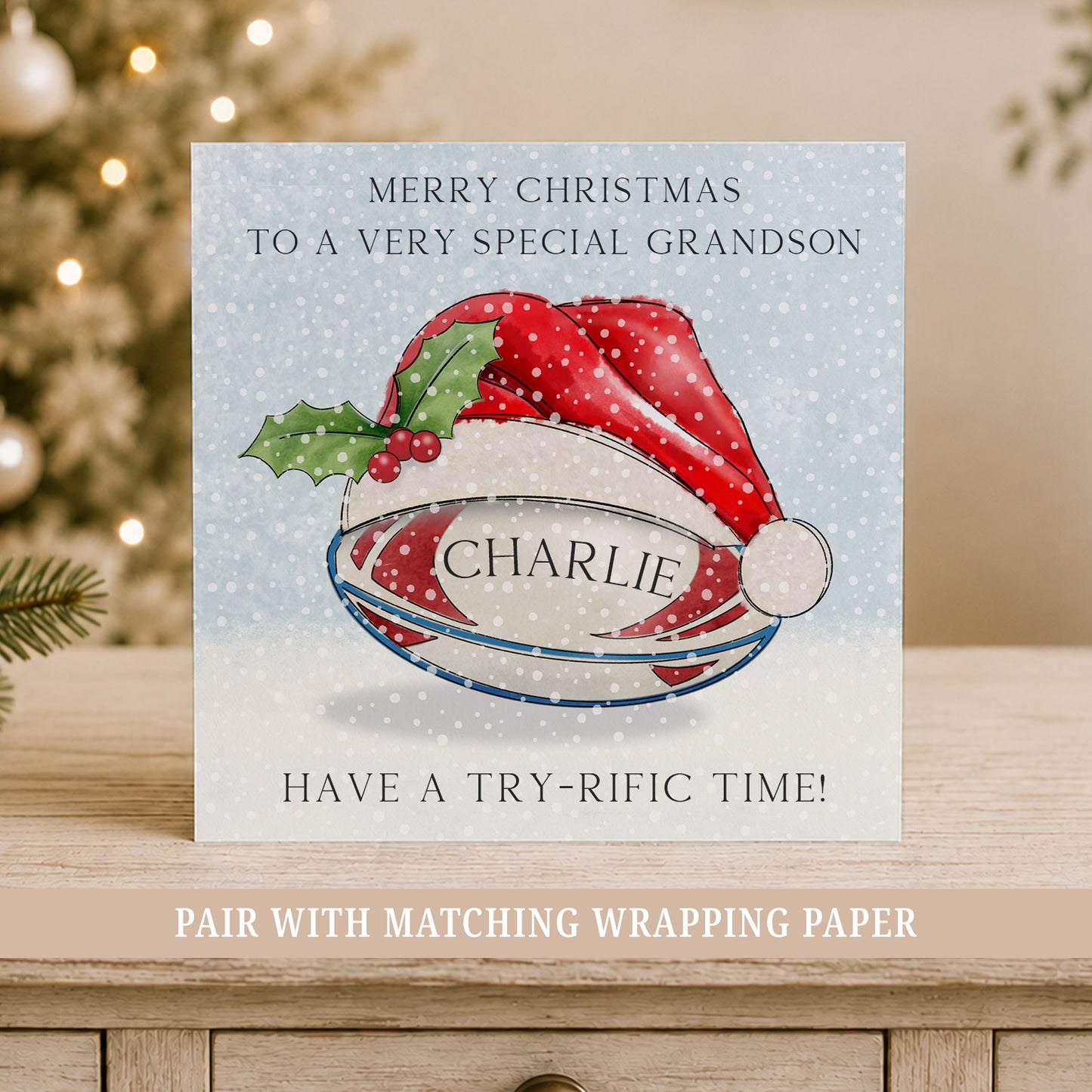 Personalised rugby Christmas card for boys featuring a rugby ball in a festive Santa hat, snowy blue background, child’s name.