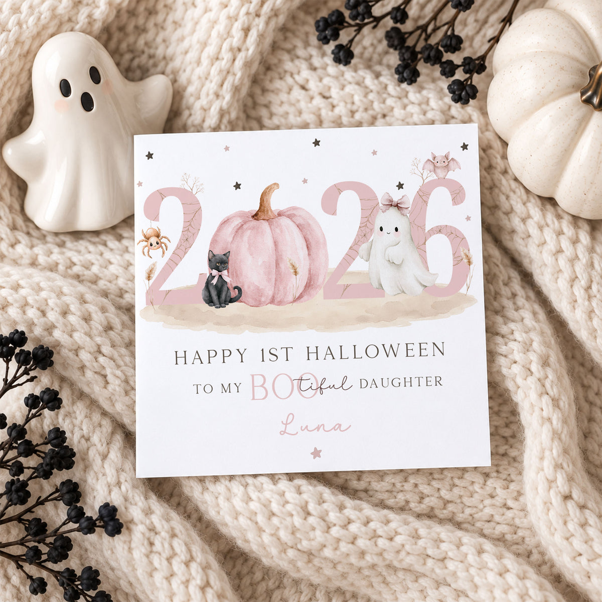 Personalised Daughter first Halloween card for 2026 with a pink pumpkin, white ghost with bow, black cat, pink bat, spider and stars. Personalised with her name and relation, with Happy 1st Halloween wording in a soft pink Halloween design for a baby girl.