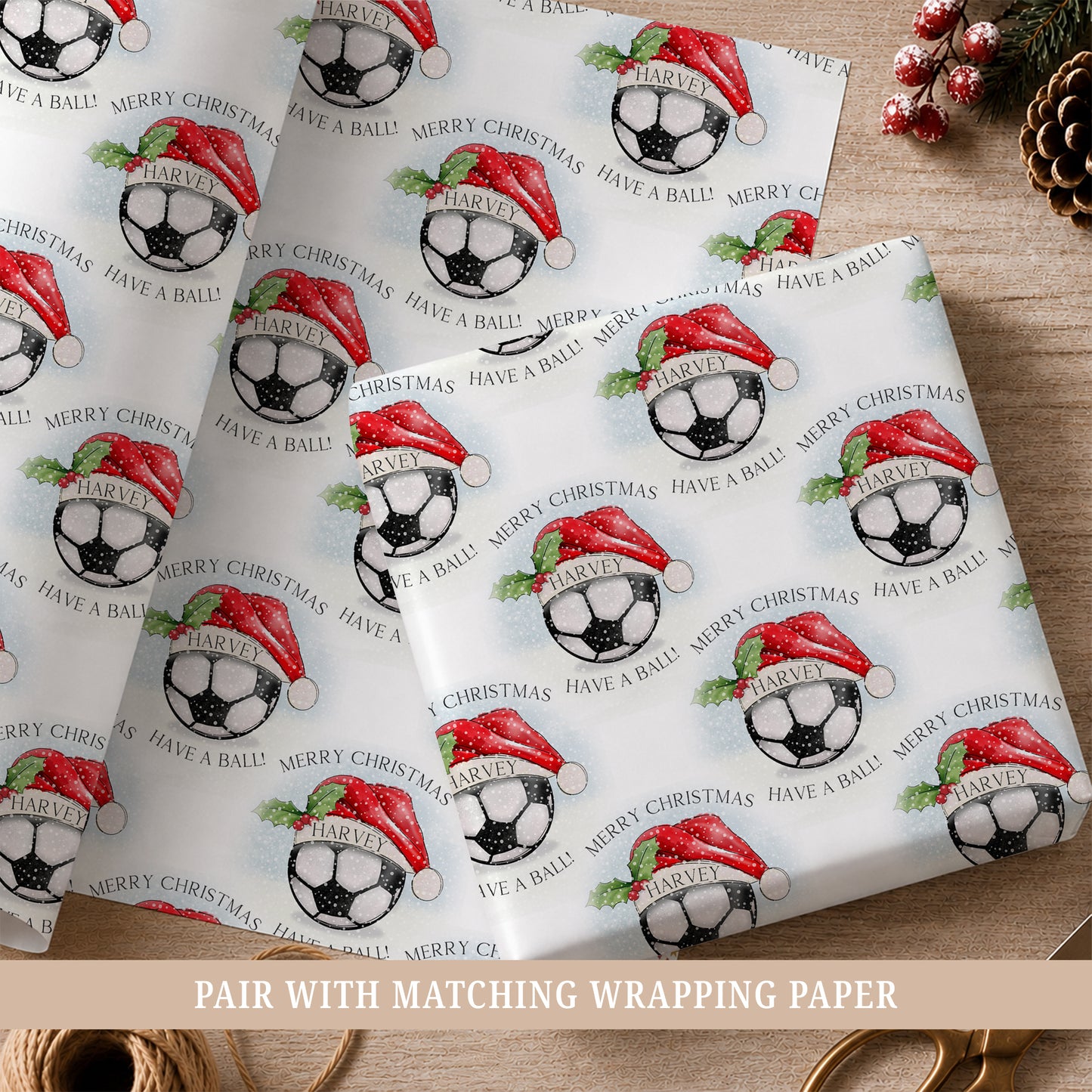Personalised football Christmas wrapping paper for boys featuring a football wearing a red Santa hat, holly, snow and the child’s name.