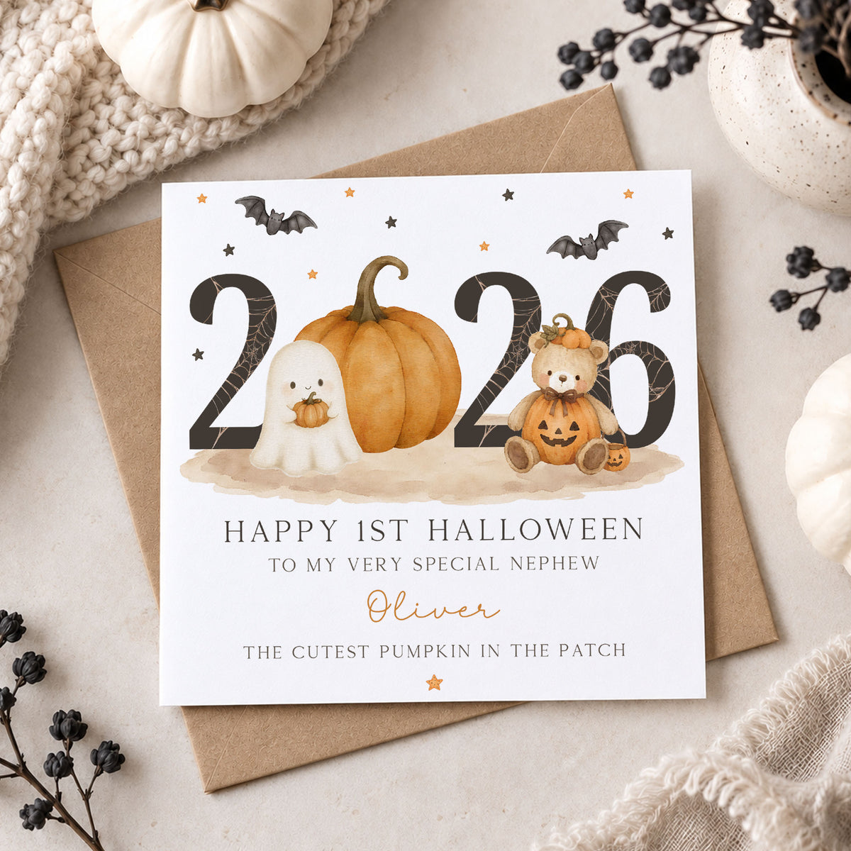 Personalised baby boy first Halloween card featuring a cute ghost, large orange pumpkin, teddy bear dressed as a pumpkin, bats and 2026 design with “The Cutest Pumpkin in the Patch” wording. Personalised with his name and available for Nephew, Grandson, Son, Godson, Little Boy and other relations.